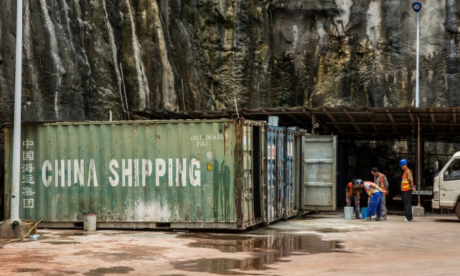 Workers stand beside a China Shipping Container Lines Co. container at the Kaleta hydroelectric dam, operated by China International Water & Electric Corp., in Kaleta, Guinea, on Sunday, Sept. 6, 2015. Guinea is in talks with China International Water & Electric Corp. to build a $2 billion hydro-power dam which would double its energy output, ensure bauxite mines can grow and allow it to become a regional power exporter, according to Lansana Fofana, the head of the nation’s hydro-power projects. Photographer: Waldo Swiegers/Bloomberg